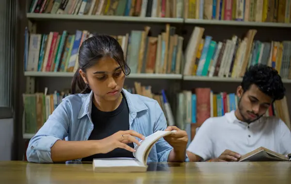 Young college students studying in the college library for their upcoming examinations. Students studying for upcoming exams. Main focus is on girl.