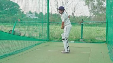 Kriket oyuncusu maç ağlarla başlamadan ısınıyor. Kriket oyuncusu net antrenman zamanında bowlingciyle karşılaşmaya hazırlanıyor. Disiplin, odaklanma, uygulama, ilerleme kavramı.