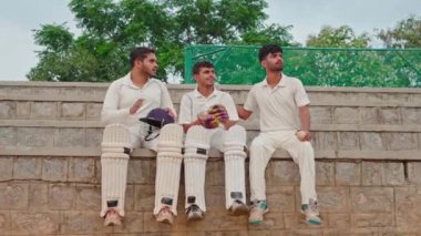 Kriket oyuncuları stadyumda oturup maçın nasıl oynandığını anlatıyorlar. Stadyumda takım arkadaşlarıyla maç hakkında tartışan oyuncular.