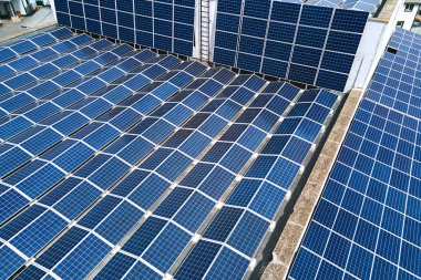 Sanayi binasının çatısına yeşil ekolojik elektrik üretmek için monte edilen mavi fotovoltaik güneş panellerinin hava görüntüsü. Sürdürülebilir enerji konsepti üretimi.