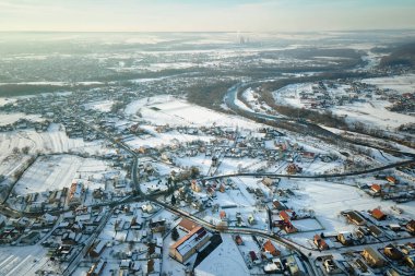 Soğuk kış mevsiminde kırsal kesimlerdeki çatıları karla kaplı özel evlerin hava manzarası..