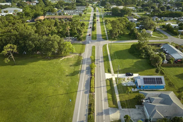 Aerial view of street traffic with driving cars in small town America suburban landscape with private homes between green palm trees in Florida quiet residential area.