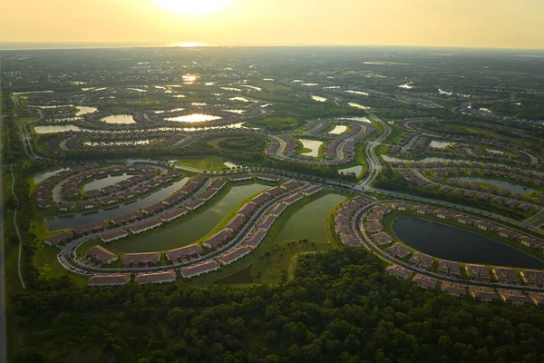 View from above of densely built residential houses near retention ponds in closed living clubs in south Florida. American dream homes as example of real estate development in US suburbs.