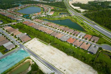 Florida 'nın kapalı banliyö bölgesinde inşaat halindeki aile evleri ile birlikte gayrimenkul gelişiminin havadan görüntüsü. Büyüyen Amerikan banliyöleri kavramı.