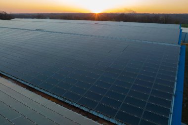 Sanayi binasının çatısına yeşil ekolojik elektrik üretmek için monte edilen mavi fotovoltaik güneş panellerinin hava görüntüsü. Sürdürülebilir enerji konsepti üretimi.