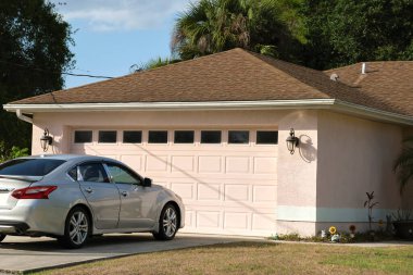 Car parked in front of wide garage double door on concrete driveway of new modern american house.