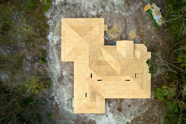 Aerial view of suburban private house with wooden roof frame under construction in Florida quiet rural area.