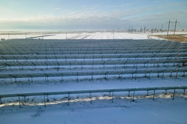 Aerial view of sustainable electrical power plant with solar photovoltaic panels covered with snow in winter for producing clean energy. Concept of low effectivity of renewable electricity in north.