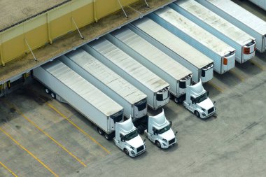 Perakende sevkiyatı için bir sürü kargo kamyonunun boşalttığı ve perakende ürün yüklediği büyük bir şirket sevkiyat merkezi. Küresel pazar kavramı.