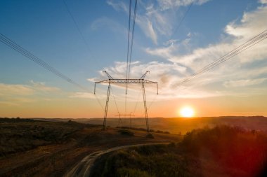 Güneş doğarken elektrik hatları olan yüksek voltaj kulesinin koyu gölgesi. Elektrik enerjisi konsepti aktarımı.