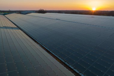 Mavi fotovoltaik güneş panelleri gün batımında temiz ekolojik elektrik üretmek için çatıya monte edildi. Yenilenebilir enerji konsepti üretimi.