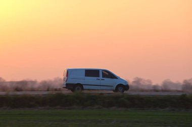 Yolcu kamyonu gün batımında şehirlerarası yolda hızla gidiyor. Akşamları otoyol trafiği.