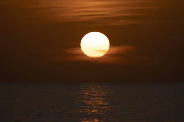 Ocean sunset. Big white sun on dramatic bright sky background, soft evening horizont over sea dark water.