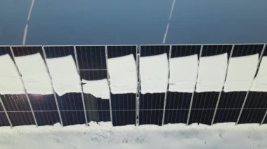Aerial view of snow melting from covered solar photovoltaic panels at sustainable electric power plant for producing clean electrical energy. Low effectivity of renewable electricity in winter.