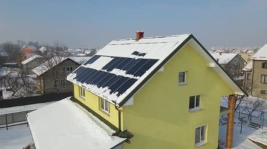 Aerial view of snow melting from covered solar photovoltaic panels installed on house rooftop for producing clean electrical energy. Low effectivity of renewable electricity in nothern region winter.