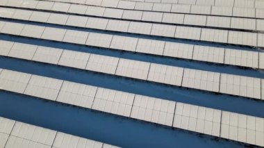 Aerial view of sustainable electrical power plant with solar photovoltaic panels covered with snow in winter for producing clean energy. Concept of low effectivity of renewable electricity in north.