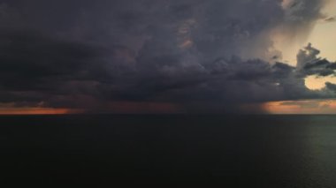 Şiddetli yağış mevsiminde akşam vakti deniz yüzeyinde kasvetli gökyüzünde kara fırtınalı bulutlar oluşur..