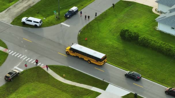 田舎町の通りで子供を拾う標準的なアメリカの黄色のスクールバスのトップビューは 早朝に彼らのレッスンのために停止します アメリカの公共交通機関 — ストック動画