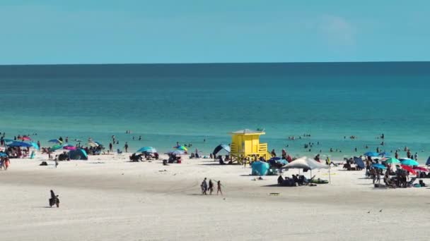 サラソータ 米国の混雑したシエスタキービーチの高角度ビュー 多くの人が海水浴や暖かいフロリダの太陽の下でリラックスした休暇を楽しんでいます — ストック動画