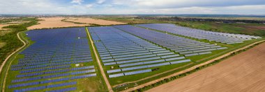Temiz ekolojik elektrik enerjisi üretmek için birçok sıra güneş fotovoltaik paneli bulunan sürdürülebilir büyük elektrik santralinin havadan görünüşü. Sıfır emisyon kavramı ile yenilenebilir elektrik.