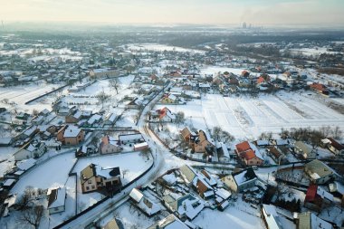 Soğuk kış mevsiminde kırsal kesimlerdeki çatıları karla kaplı özel evlerin hava manzarası..