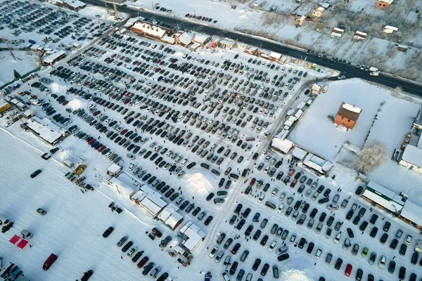 Aerial view of many cars parked for sale and people customers walking on car market or parking lot in winter.