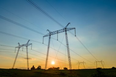 Güneş doğarken elektrik hatları olan yüksek voltajlı kulelerin koyu gölgesi..
