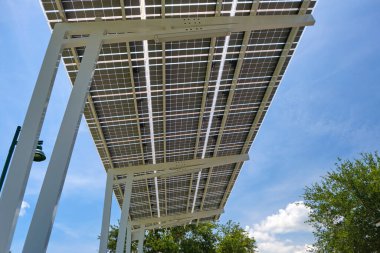 Solar panels installed over parking lot canopy shade for parked cars for effective generation of clean energy.