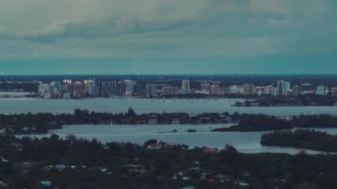 Geceleri ABD 'nin Florida kentindeki Sarasota şehrinin hava görüntüsü. Ufuktaki yüksek gökdelenler ve ofis binaları ve öndeki yeşil banliyöler.