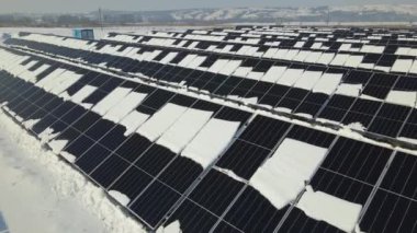 Aerial view of electrical power plant with solar panels covered with snow melting down in winter end for producing clean energy. Concept of low effectivity of renewable electricity in northern region.