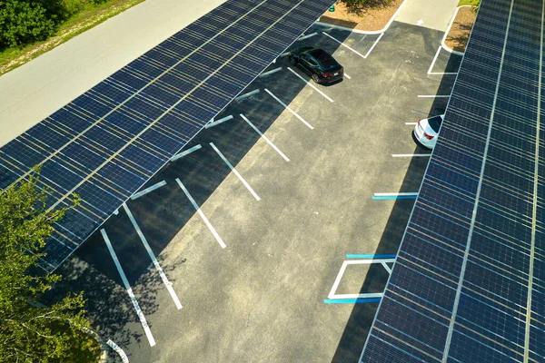Aerial view of solar panels installed as shade roof over parking lot for parked cars for effective generation of clean electricity. Photovoltaic technology integrated in urban infrastructure.