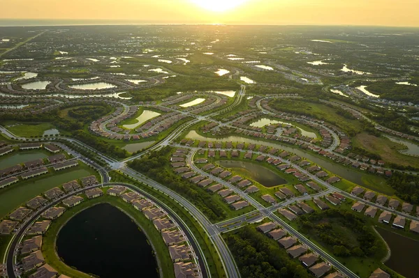 Aerial view of tightly located family houses with retention ponds to prevent flooding in Florida closed suburban area. Real estate development in american suburbs.