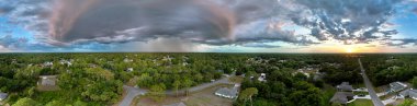 Dark stormy clouds forming on gloomy sky during heavy rainfall season over suburban town area in evening.