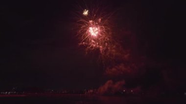 Aerial view of bright fireworks exploding with colorful lights over sea shore on US Independence day holiday.