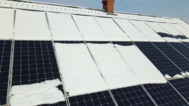 Aerial view of house roof with solar panels covered with snow melting down in winter end for producing clean energy. Concept of low effectivity of renewable electricity in northern region.