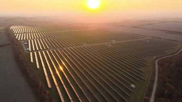 夕方にきれいな電気エネルギーを生成するための太陽光発電パネルの行を持つ大規模な持続可能な電気発電所の空中ビュー 排出ゼロの再生可能エネルギーの概念 — ストック動画