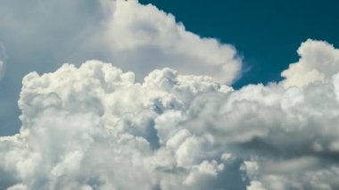 Yazın mavi gökyüzünde fırtınadan önce beyaz tüylü kümülonimbus bulutları oluşuyor. Hareket eden ve değişen bulutlu hava durumu.