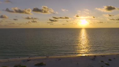 Summser denizi üzerinde gün batımının tadını çıkaran insanların karanlık siluetlerini gösteren hava manzarası..