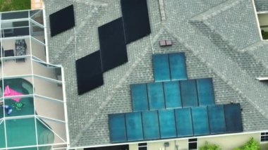 Temiz ekolojik elektrik enerjisi üretmek için mavi güneş fotovoltaik panelleri olan normal Amerikan ev çatısı. Sıfır emisyon kavramı ile yenilenebilir elektrik.