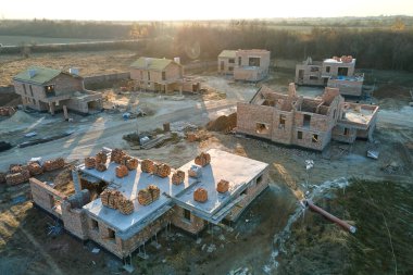 Kenar mahallelerde inşaat halindeki tuğla iskelet duvarları olan yeni evlerin havadan görünüşü. Modern şehir banliyölerinde gayrimenkul geliştirme.