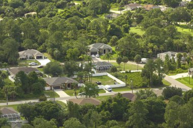 Florida 'nın sakin yerleşim bölgesinde yeşil palmiye ağaçları arasında özel evleri olan küçük bir Amerikan banliyö manzarası..