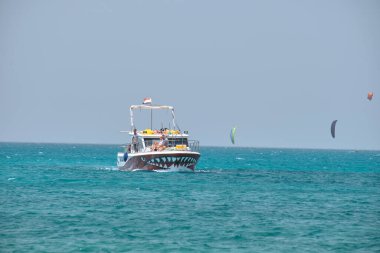 Mavi deniz suyunun dalgalı yüzeyi ve durgun dalgalarda yüzen beyaz sürat teknesiyle deniz manzarası..