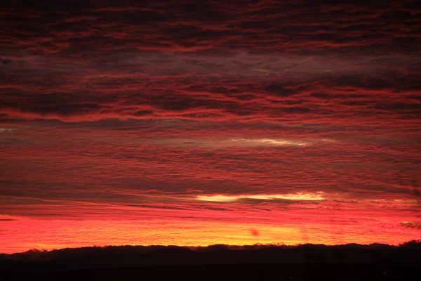 太陽の光が地平線に広がる設定で照らされた鮮やかな滑らかな雲と明るいカラフルな夕日の空 — ストック写真