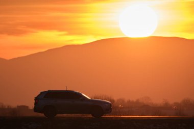 Gün batımında şehirlerarası yolda hızla giden bir SUV arabası. Akşamları otoyol trafiği.