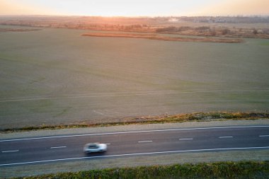 Bulanık hızlı sürüş yapan şehirlerarası yolun hava manzarası gün batımında çevre dostu elektrikli araba. Akşamları otoban trafiğinin insansız hava aracı görüntüsü.