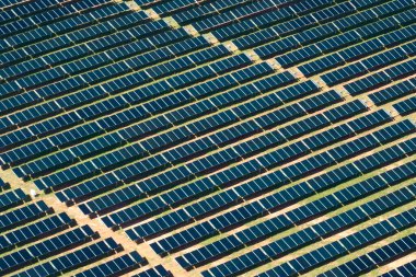 Temiz elektrik enerjisi üretmek için sıra sıra güneş fotovoltaik panelleri olan sürdürülebilir büyük elektrik santralinin havadan görünüşü. Sıfır emisyonlu yenilenebilir elektrik kavramı.