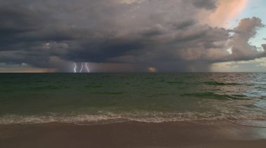Şiddetli yağış mevsiminde akşam vakti deniz yüzeyinde kasvetli gökyüzünde kara fırtınalı bulutlar oluşur..