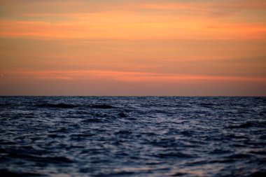 Dramatic red ocean waves at sunset with soft evening sea dark water.
