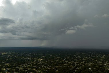 Landscape of dark ominous clouds forming on stormy sky during heavy thunderstorm over rural town area.