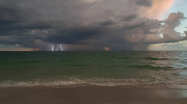 stock image Dark stormy clouds forming on gloomy sky during heavy rainfall season over sea surface in evening.